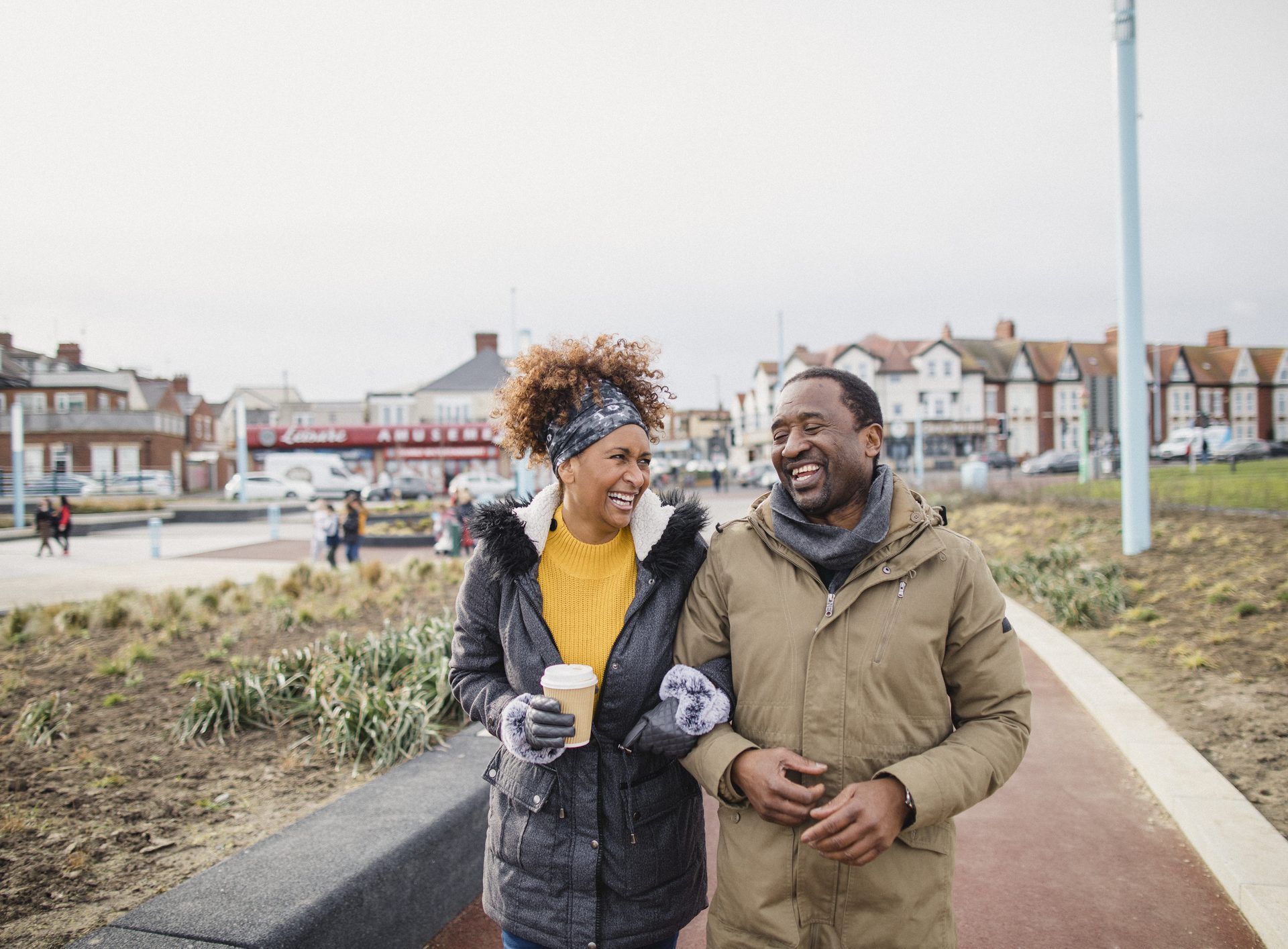 Man and a woman walking arm-in-arm and laughing